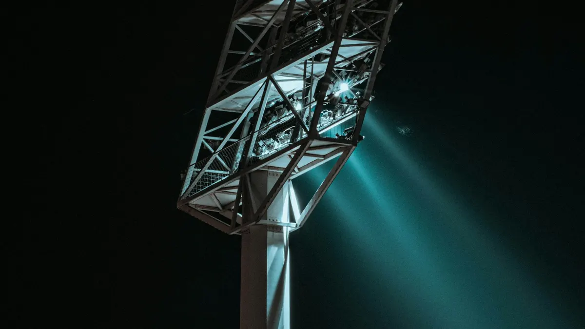 Fußballstadion bei Flutlicht, im Vordergrund ein Fernseher mit Sportsendung